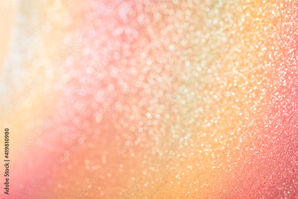 Iridescent rainbow background with orange and yellow glitter. Gradient stock texture with fine sparkles