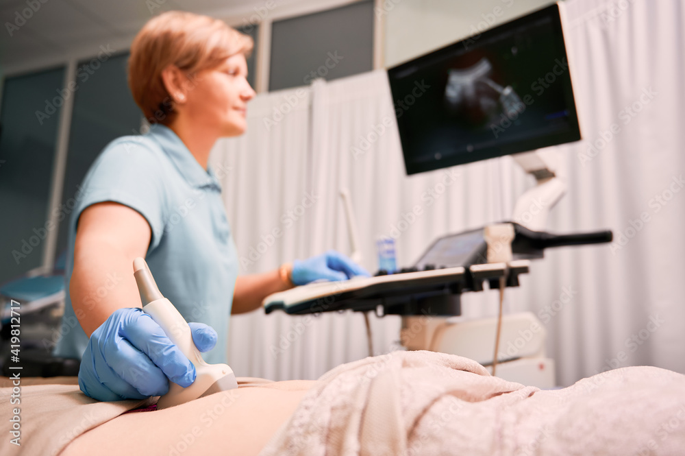 Obraz premium Doctor performing ultrasound procedure in modern clinic.