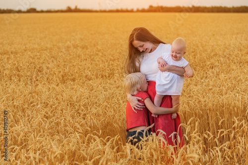 Beautiful Young mother with two children walking through wheat field. Weekend in countryside © somemeans