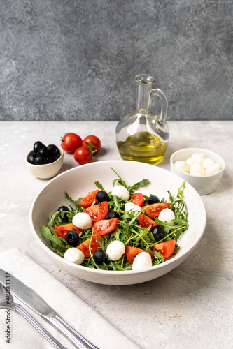 Mozzarella salad with tomatoes black olives arugula and olive oil. dish of Italian Greek cuisine. Healthy eating