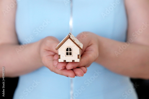 Wooden house in female hands, real estate agent. Woman with house model, concept of insurance, purchase or rental home