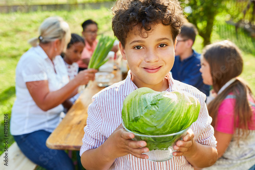 Kind mit Salatkopf im Kochkurs für gesunde Ermährung