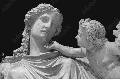 Antique statue of Eirene with the infant Ploutos isolated on black background. Goddess of Peace beautiful young woman carrying a cornucopia