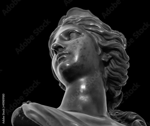 Ancient white marble sculpture head of young woman. Statue of sensual renaissance art era woman antique style. Face isolated on black background