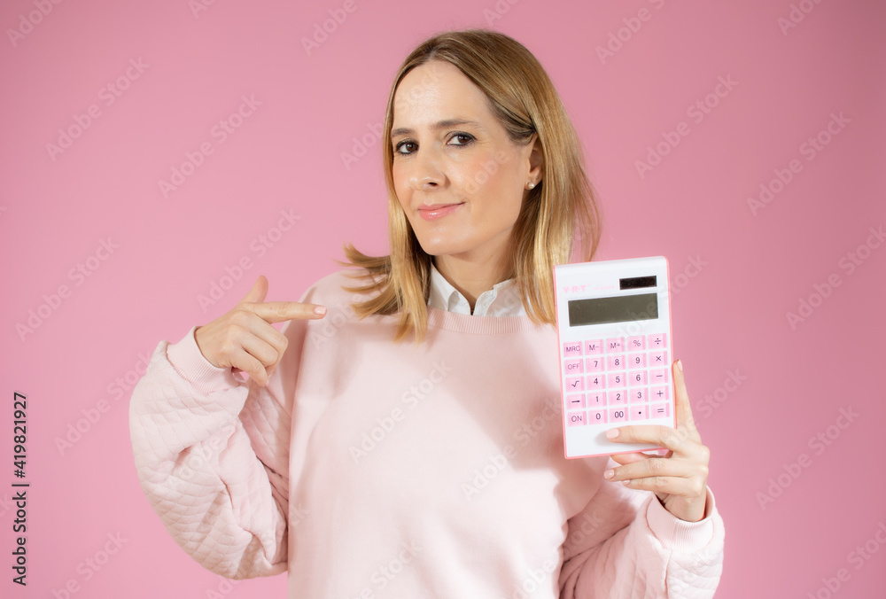 Young smiling woman with calculator on pink background Young smiling woman with calculator on pink background