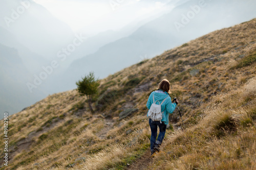 Woman with backpack is trekking on foggy mountain. Tourist traveler on background view mockup. Local travel during a pandemic and self-isolation. Back view person. opy space