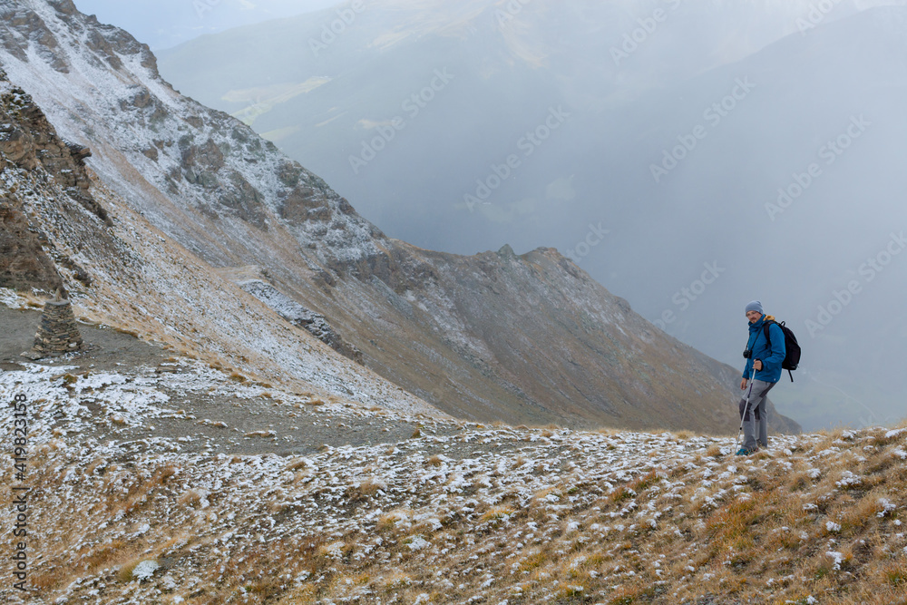 Solo traveler walks along a mountain valley. New reality, isolation, lonely journey. Spring view trekking in the fresh air. Back view of man with a backpack. Scenic picture with copy space