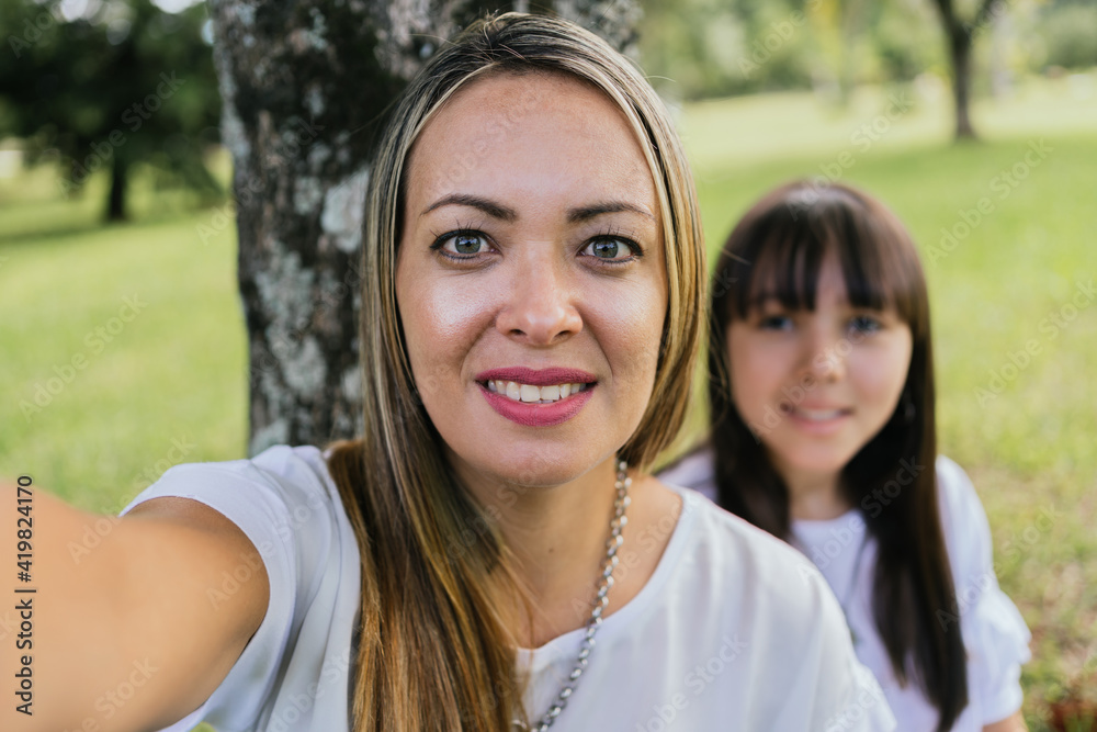 Portrait of Latina mother and daughter in a garden.