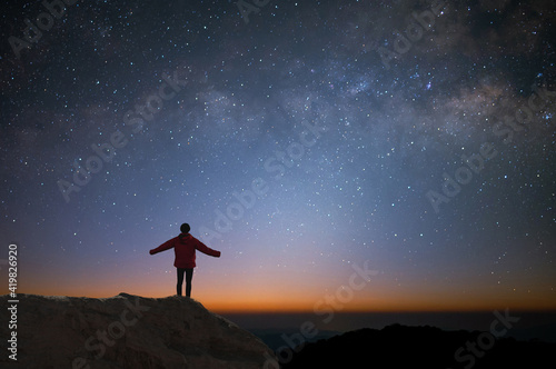 Silhouette of young traveler and backpacker watched the star and milky way alone on top of the mountain. He enjoyed traveling and was successful when he reached the summit.