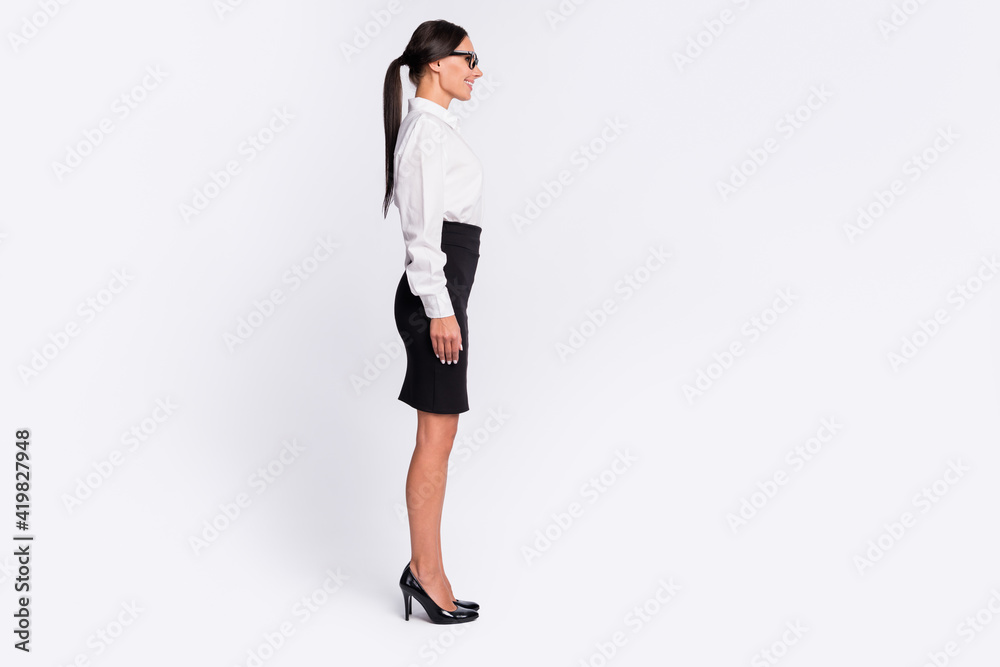 Full size profile photo of optimistic brunette hairdo lady near empty space wear spectacles shirt skirt isolated on grey background Full size profile photo of optimistic brunette hairdo lady near empty space wear spectacles shirt skirt isolated on grey background