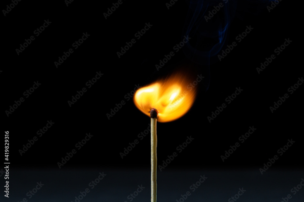 Burning match on a black background. A light from a match on a dark background. Burning match on a black background. A light from a match on a dark background.