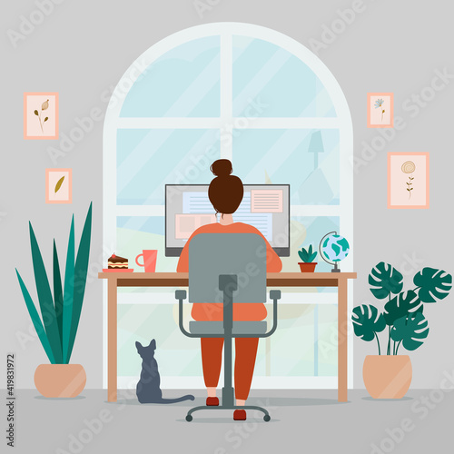Woman working at home on computer. Cozy creative workplace homeoffice with plants, paintings and cat. Freelance concept.