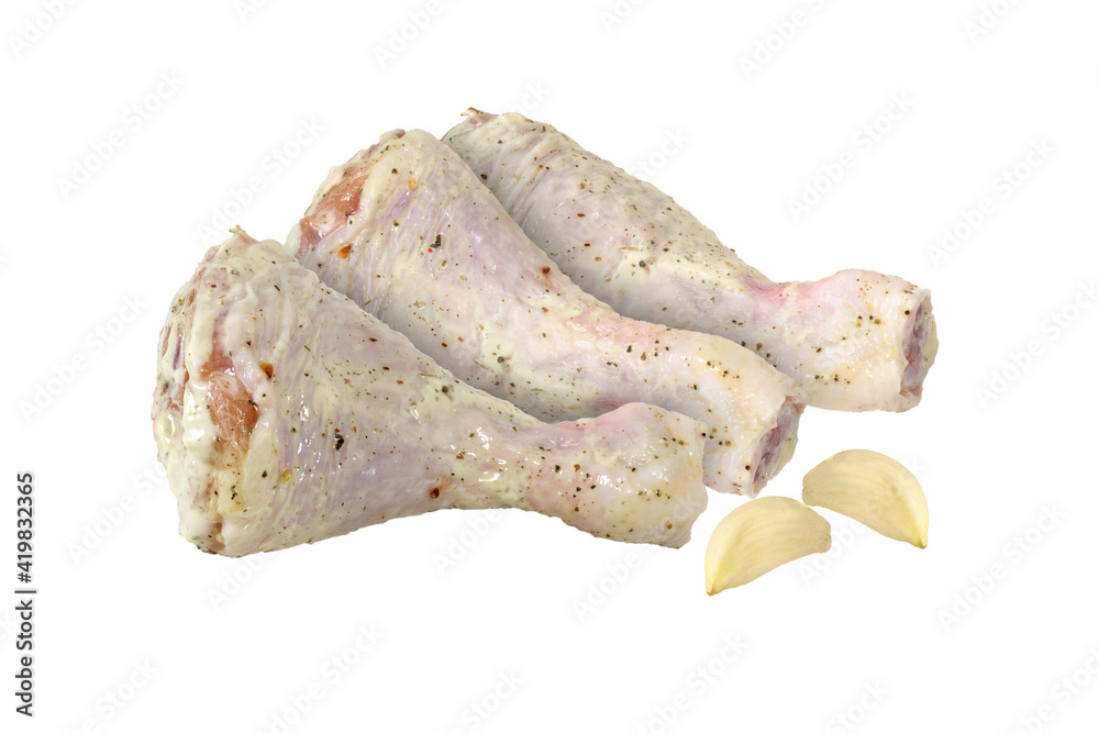 Raw marinated chicken legs and cloves of garlic on an isolated white background. Raw marinated chicken legs and cloves of garlic on an isolated white background.