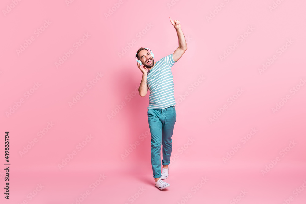 Full length body size view of nice cheerful guy walking enjoying listening melody having fun rest isolated over pink color background Full length body size view of nice cheerful guy walking enjoying listening melody having fun rest isolated over pink color background