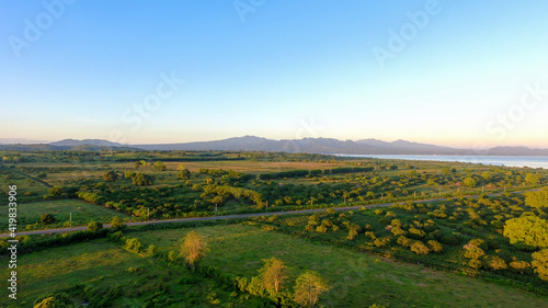 Fototapeta Naklejka Na Ścianę i Meble -  Aerial panoramic View of a scenic Highway surrounded green field Landscape during a summer morning