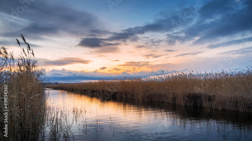 dramatic sunset on a canal at lake Neusiedlersee with reeds on the shore