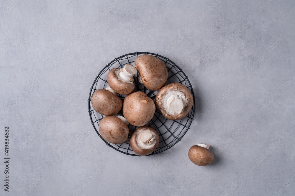 Obraz premium Royal mushrooms lie in a basket, which lies on a gray background.