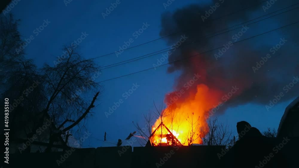 The roof of the house is on fire. The residential building burn, village. Firefighters put out a fire from the crane from above. The fire Department putting out the open flame. Smoke and sparks.
