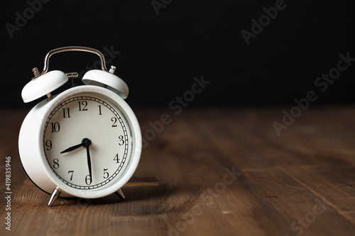 Retro alarm clock on wooden background. back to work and school concept.