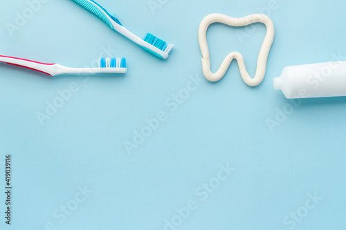 Tooth shape with tube of toothpaste and toothbrush. Dental hygiene concept, top view