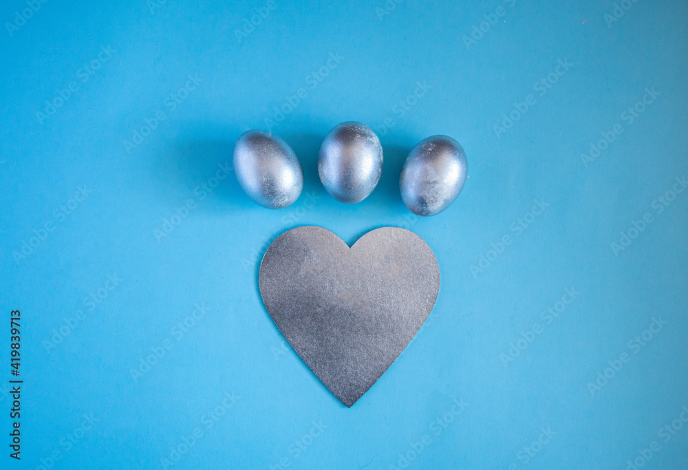 Obraz premium Silver eggs and decorative silver heart on delicate blue background. concept of rich Easter holidays, greeting cards and spring love.