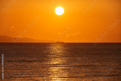 a cargo ship passes at the first light of the new day in the distance setting sail from the coast of Calabria