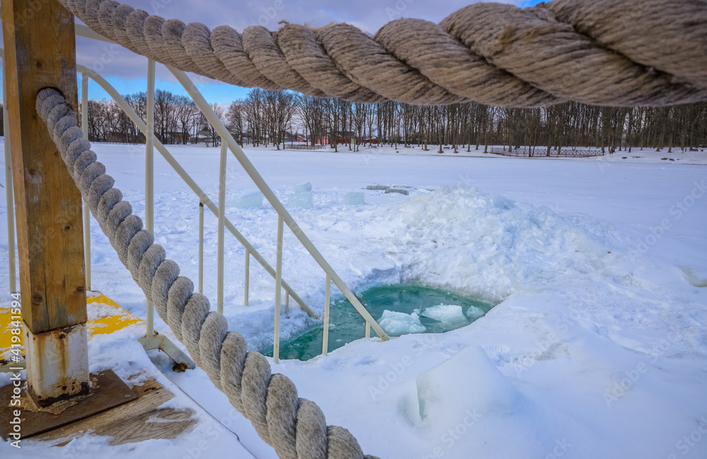 Naklejka premium Bridge over the river surrounded by rope. Ice-hole for winter swimming.