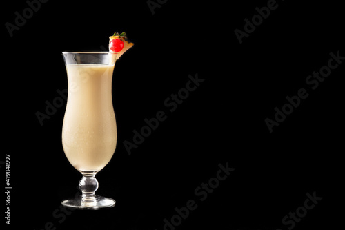 Pina colada cocktail in glass on black background. Copy space