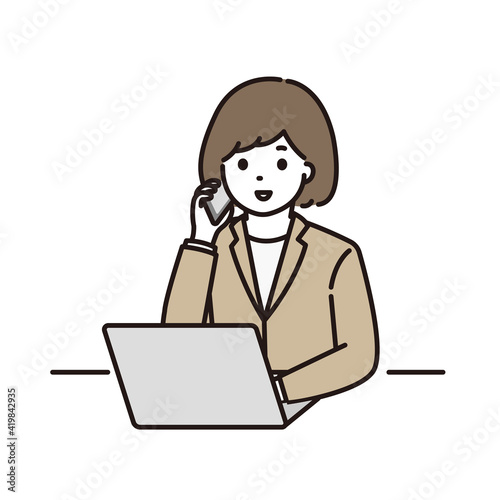 パソコンの前で電話をするスーツ姿の若い女性