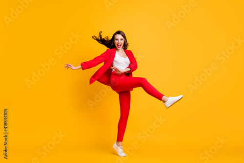Full length photo of pretty classy girl dance open mouth wear red suit jacket trousers sneakers eyewear isolated yellow color background