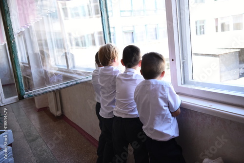 Four teenagers look out the window at school. Back view. Copy space. 