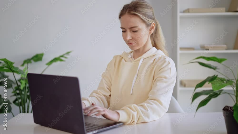 portrait young woman typing onlaptop at home office freelancer in casual hoodie portrait young woman typing onlaptop at home office freelancer in casual hoodie