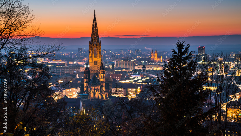 Germany, Freiburg im Breisgau, Magical red sunset sky above skyline of the beautiful city and muenster by night in blue hour atmosphere
