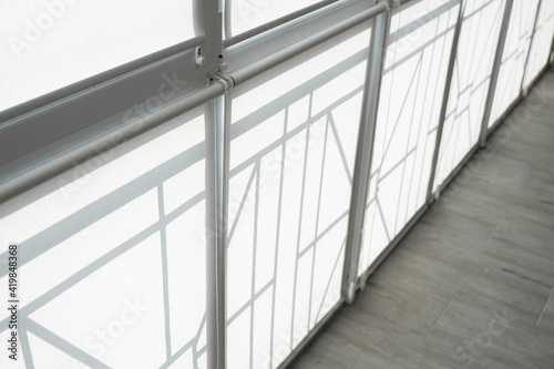 White fabric roller blinds on the plastic window on a balcony in the living room.