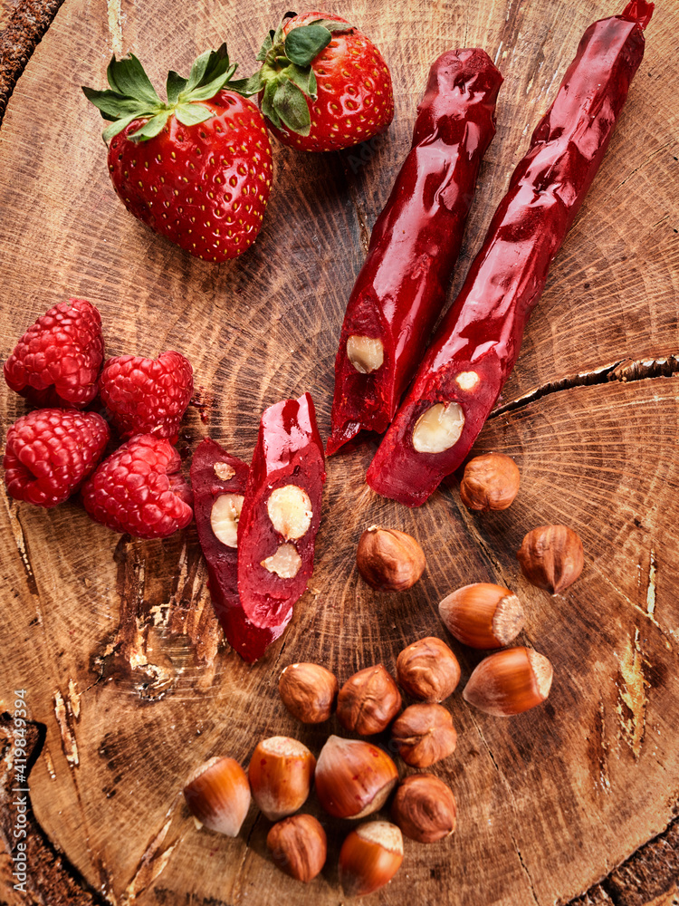 slicing Churchkhela, strawberries and nuts on a wooden background, top view, serving slicing Churchkhela, strawberries and nuts on a wooden background, top view, serving