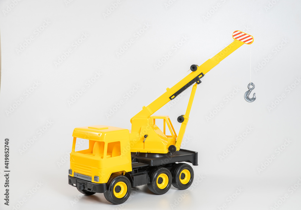 Plastic car. Toy model isolated on a white background. Yellow truck mounted crane.