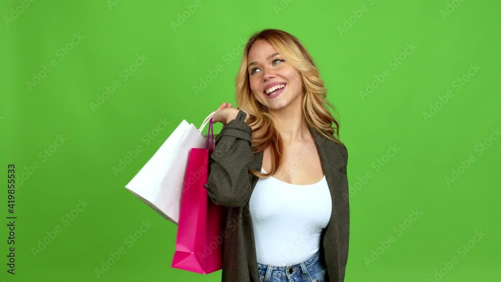 Young blonde girl holding shopping bags isolated on background on green screen chroma key Young blonde girl holding shopping bags isolated on background on green screen chroma key