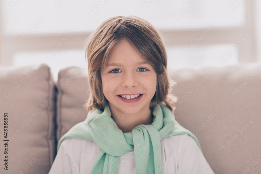Photo portrait of smiling boy sitting at home on couch wearing casual clothes Photo portrait of smiling boy sitting at home on couch wearing casual clothes