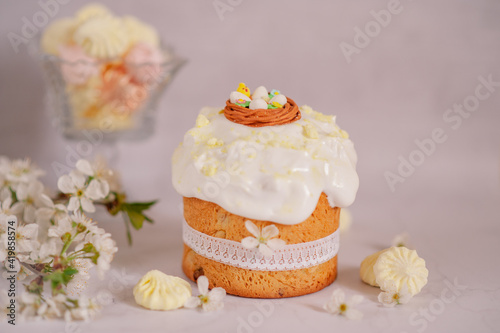 Traditional Easter cake with white icing and Easter eggs on a light background with cherry blossom branches photo