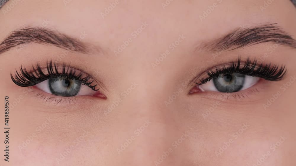 Close up portrait of female eyes after eyelash extension procedure. Young girl open eyes with fake eyelashes. Eyelashes extensions close up.
