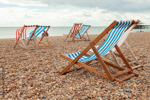 Pairs of empty red and blue striped hammocks available for hire on the beach in the southern UK town of Brigthon near the West Pier. © Alvaro