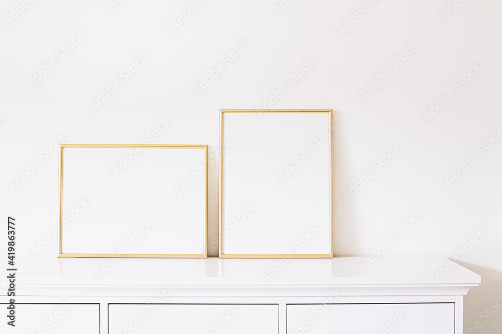Two golden vertical and horizontal frames on white furniture, luxury