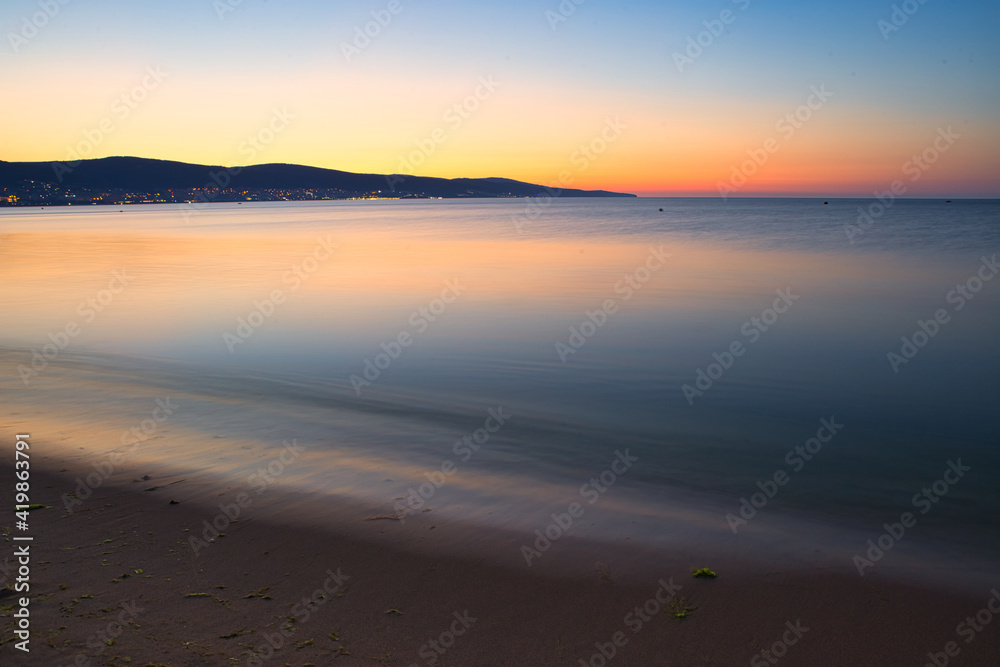 Still blue sea water under colorful evening cloudy sky Still blue sea water under colorful evening cloudy sky