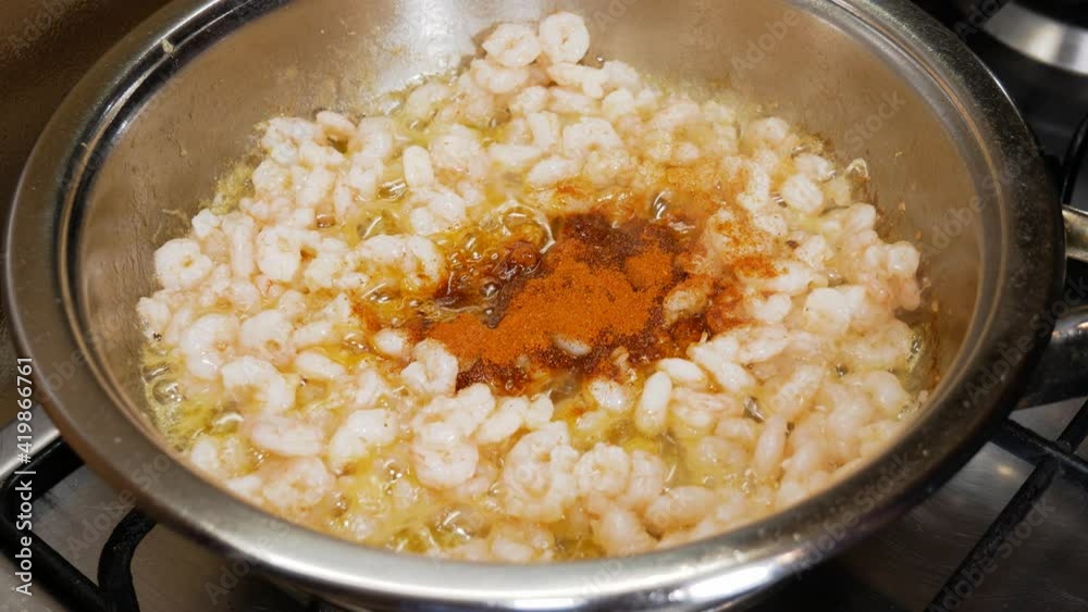 Mixing small fresh shrimps with bell pepper powder in steaming hot pot Mixing small fresh shrimps with bell pepper powder in steaming hot pot