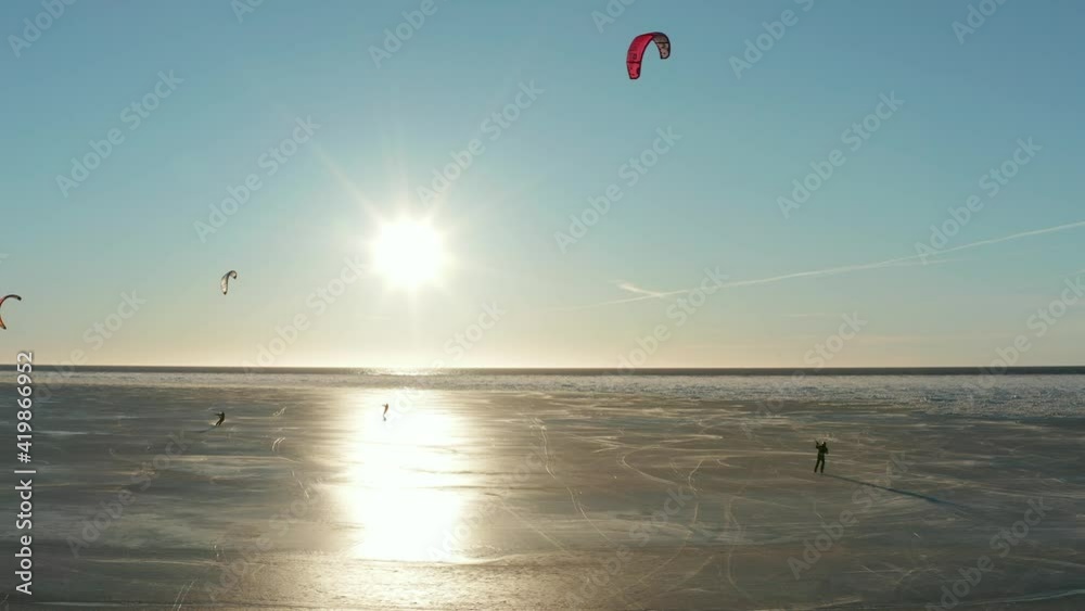Beautiful drone shot of kite boarding over frozen sea in a sunny day. Camera pan to left. 4k footage Beautiful drone shot of kite boarding over frozen sea in a sunny day. Camera pan to left. 4k footage