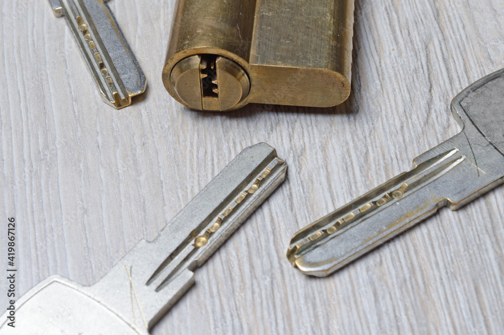 the disassembled door lock and the keys to it lie on a light surface. close-up.