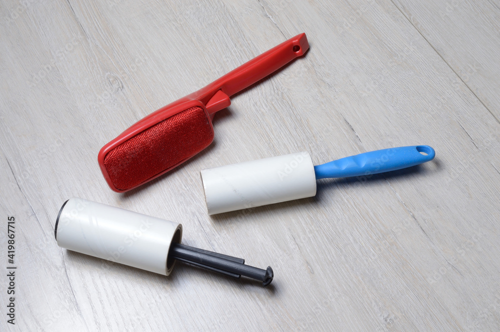 brushes for cleaning clothes. sticky and a bristled brush, lie on a light-colored countertop.