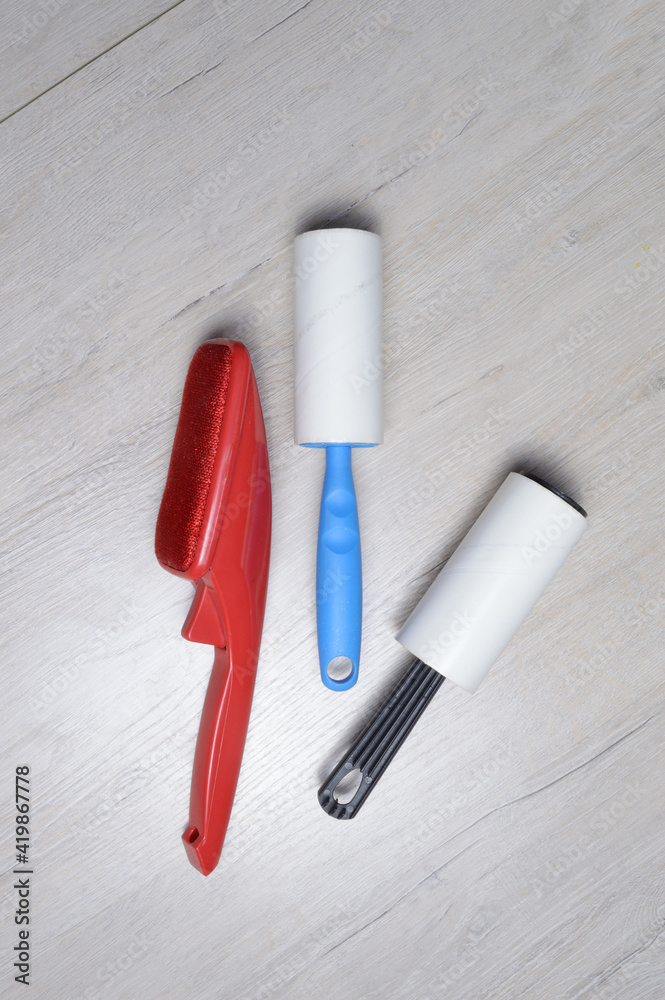 brushes for cleaning clothes. sticky and a bristled brush, lie on a light-colored countertop.