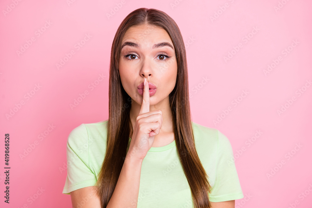 Photo of sweet pretty young girl dressed green t-shirt finger lips ask not tell secrets isolated pastel pink color background Photo of sweet pretty young girl dressed green t-shirt finger lips ask not tell secrets isolated pastel pink color background