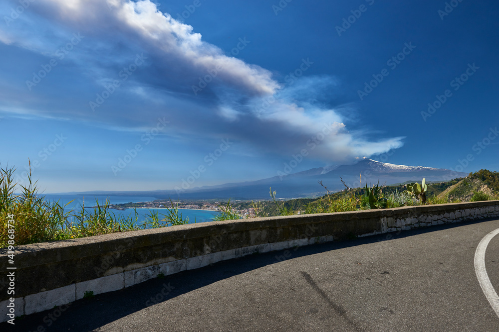 Fototapeta premium volcano in Sicily taken from the road that climbs to get to Taormina on a beautiful sunny day in spring 2021, you can see the station and Giardini Naxos with the whole 
